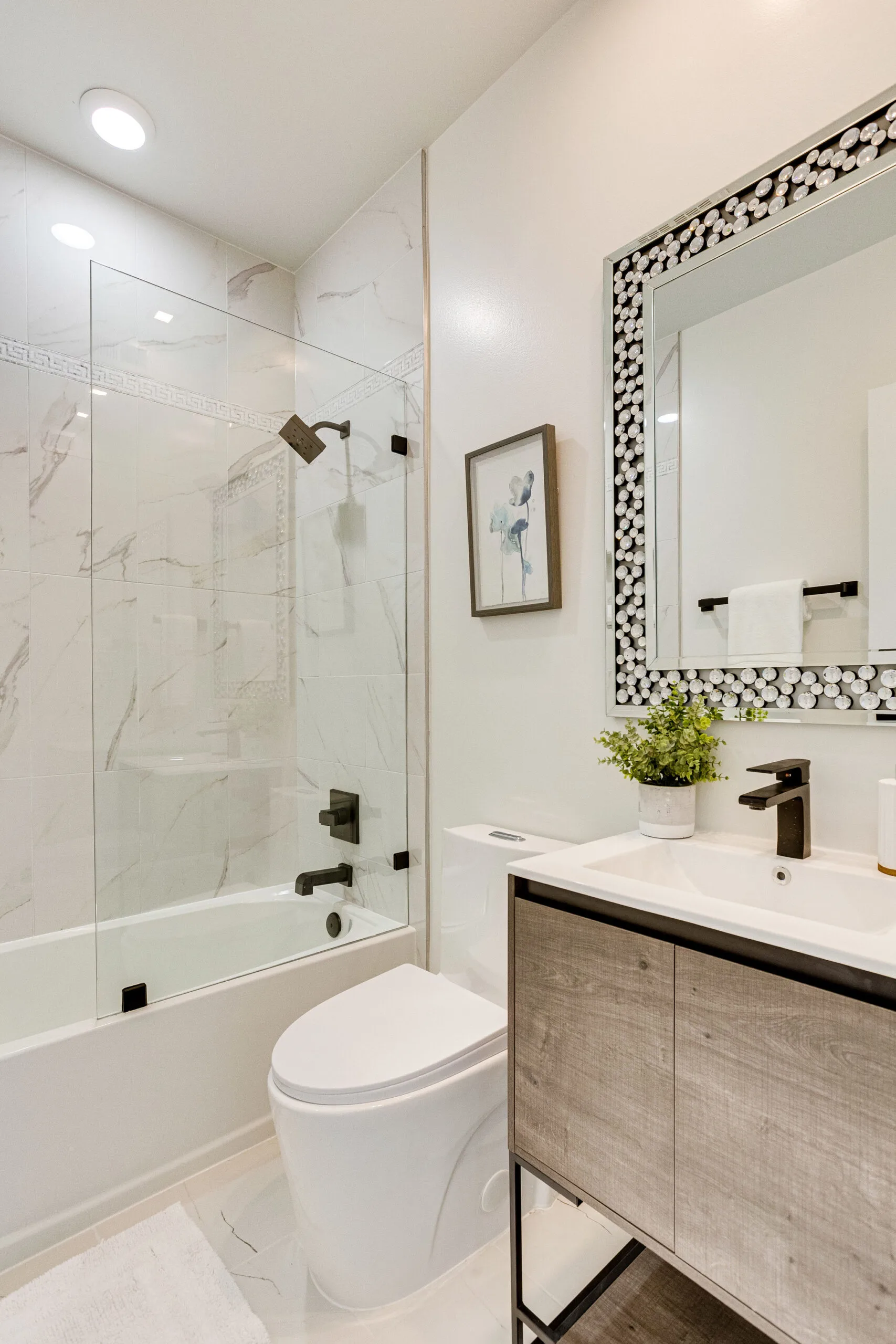 A marble shower and white vanity with black fixtures